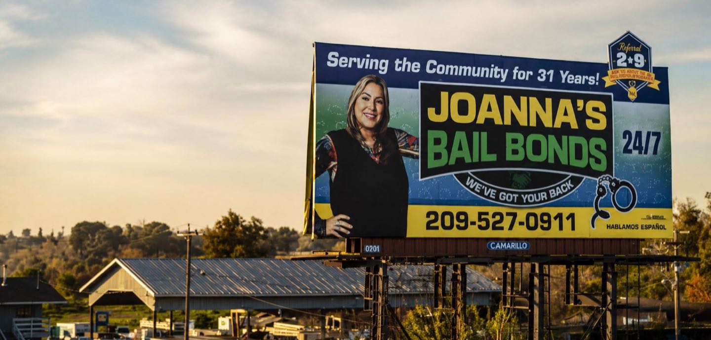 Joanna's Bail Bonds billboard at sunset — serving the community, 24/7